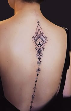 the back of a woman's neck with an intricate tattoo design on her left shoulder