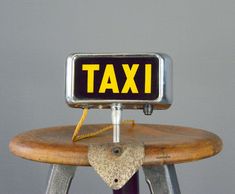 a taxi sign sitting on top of a wooden chair next to a metal object with a cord