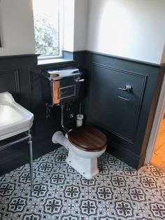 a toilet and sink in a small room with black walls, patterned flooring and white fixtures