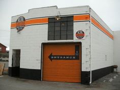 an orange and white building with a black arrow pointing to the door that says orange