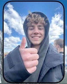 a young man giving the thumbs up sign