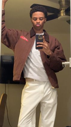 a man taking a selfie in the mirror with his cell phone and wearing white pants