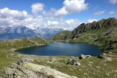 a large lake surrounded by mountains under a blue sky with white clouds in the distance