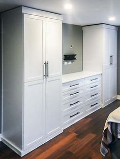 an empty bedroom with white cabinets and drawers