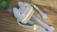 a crocheted cat sitting on top of a wooden floor next to a potted plant