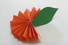 an origami flower with green leaves on the top and orange petals on the bottom