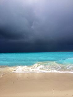 the ocean is blue and green as storm clouds loom overhead