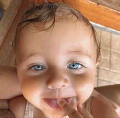 a baby with blue eyes is brushing his teeth