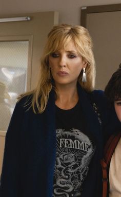 two women standing next to each other in front of a mirror with one woman looking at the camera