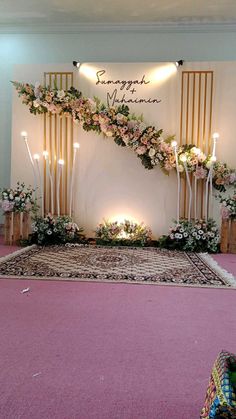 a decorated stage with candles and flowers on the floor in front of a large sign