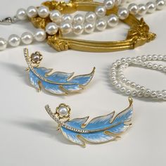 This exquisite piece features a meticulously crafted feather design, adorned with lustrous pearls, evoking the serene beauty of swans gliding across a tranquil lake. A symbol of elegance and grace, it's perfect for adding a touch of sophistication to any outfit. Composition: enamel, pearls, zircon, gold-plated brass Avoid exposure to harsh chemicals, such as perfume, hairspray, and cleaning agents. Store your metal jewelry in a dry and cool place to prevent tarnishing. Use a soft cloth to gently clean your jewelry after each wear to remove dirt and sweat. If your jewelry becomes tarnished, use a specialized cleaning solution or a mixture of baking soda and water to remove it. Avoid wearing metal jewelry when swimming or showering to prevent damage. Remove your jewelry before exercising or Swan Brooch, Forever Jewelry, Feather Design, Swan Lake, Jewelry Ring Box, Pearl Brooch, Mens Jewelry Bracelet, Swans, Watch Necklace