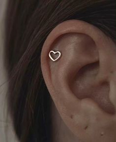 a woman's ear is shown with a heart shaped piercing on the side of her ear