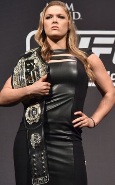 a woman standing in front of a sign with her hands on her hips and wearing a leather outfit