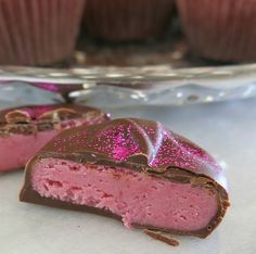 two pieces of chocolate and pink cake with sprinkles on them sitting next to each other