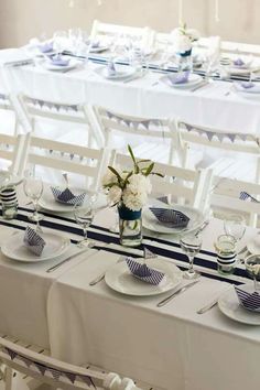 the table is set with blue and white plates, silverware, and vases