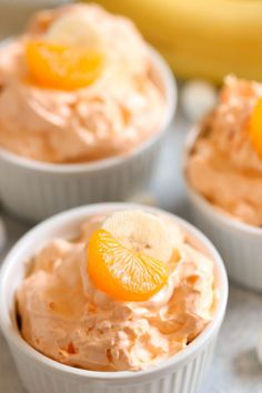 three small white bowls filled with food on top of a table next to bananas and orange slices