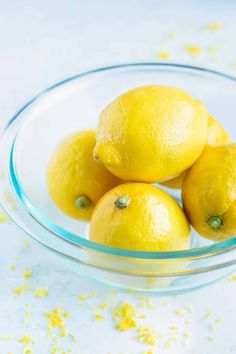 three lemons in a glass bowl on a table