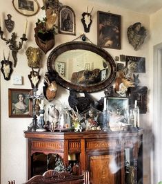 a room with many different types of animal heads on the wall and an antique dresser