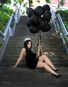 a woman is sitting on the stairs with balloons in her hand and wearing a tiara