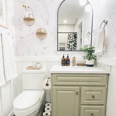 a white toilet sitting under a bathroom mirror next to a sink with a mirror above it