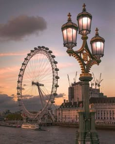 a large ferris wheel sitting in the middle of a river next to tall buildings with lights on them