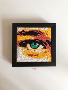 a painting with an orange tiger's face and green eyes in a black frame