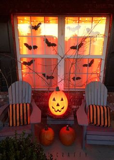 two chairs sitting in front of a window decorated for halloween with pumpkins and bats