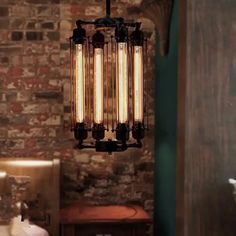 an old fashioned chandelier hangs from the ceiling in a brick walled bathroom area