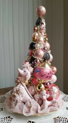 a pink and gold christmas tree on top of a doily