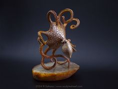 an octopus sculpture on top of a piece of rock with its mouth open and eyes closed