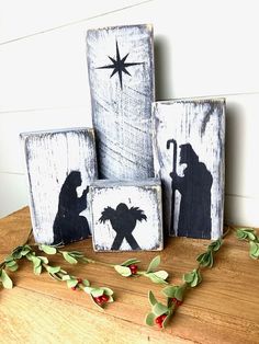 three wooden blocks decorated with silhouettes of people and a star on the top one