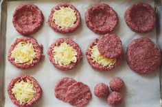 raw hamburger patties on a baking sheet ready to go into the oven with cheese