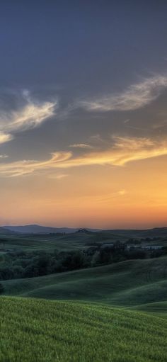 the sun is setting over an open field