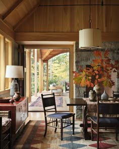 a living room filled with furniture and a large window covered in fall leaves on the wall