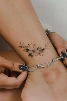 a woman with a flower tattoo on her arm and foot is holding onto another woman's ankle