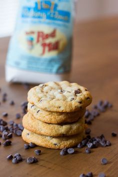 chocolate chip cookies are stacked on top of each other next to a bag of milk