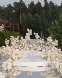 an outdoor ceremony with white flowers and candles in the center, surrounded by tall trees