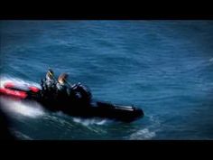 two people riding on the back of a small boat in the middle of the ocean