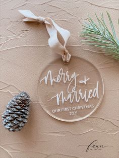 a glass ornament with the words merry and married on it next to a pine cone