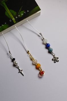 three necklaces with charms on them sitting next to a book