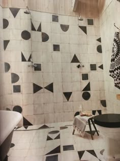 a bathroom with black and white tiles on the walls, flooring and bathtub