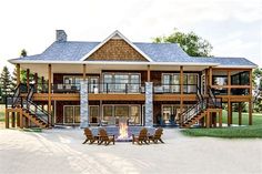 an image of a house that is in the middle of some grass with chairs around it