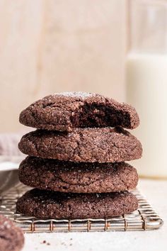 chocolate cookies stacked on top of each other with a glass of milk in the background