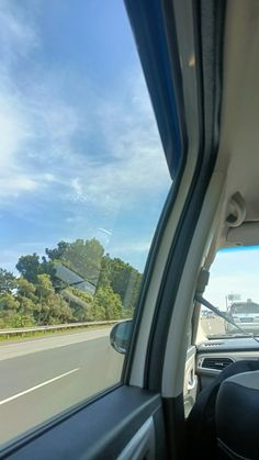 view from inside the passenger seat of a car driving on a highway with trees in the background