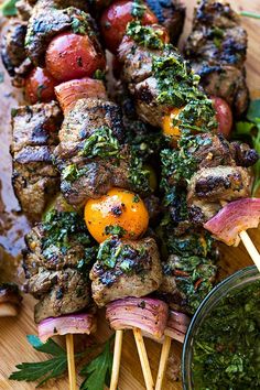 several skewers with meat and vegetables on them sitting on a wooden cutting board