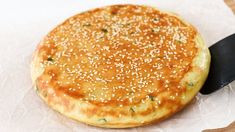 a close up of a pastry on wax paper with sesame seed sprinkles