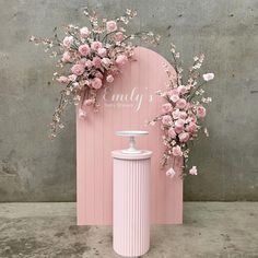 a pink vase with flowers next to a pink sign