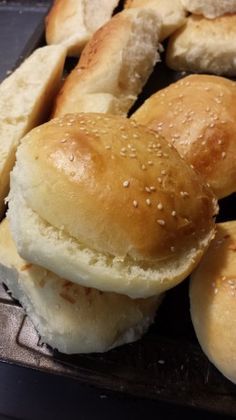 rolls with sesame seeds on them sitting in a baking pan