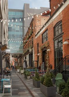 an empty city street with tables and chairs on both sides, surrounded by tall buildings