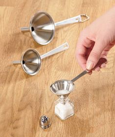 a person is holding a spoon over some kitchen utensils on a wooden table